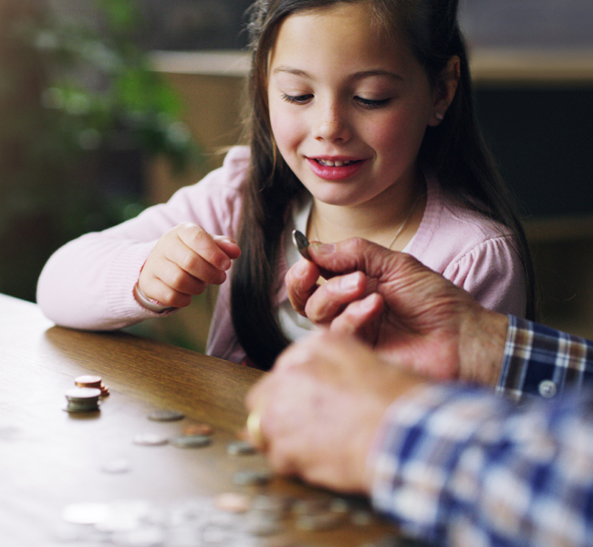 Young girl and man looking at coins on table
